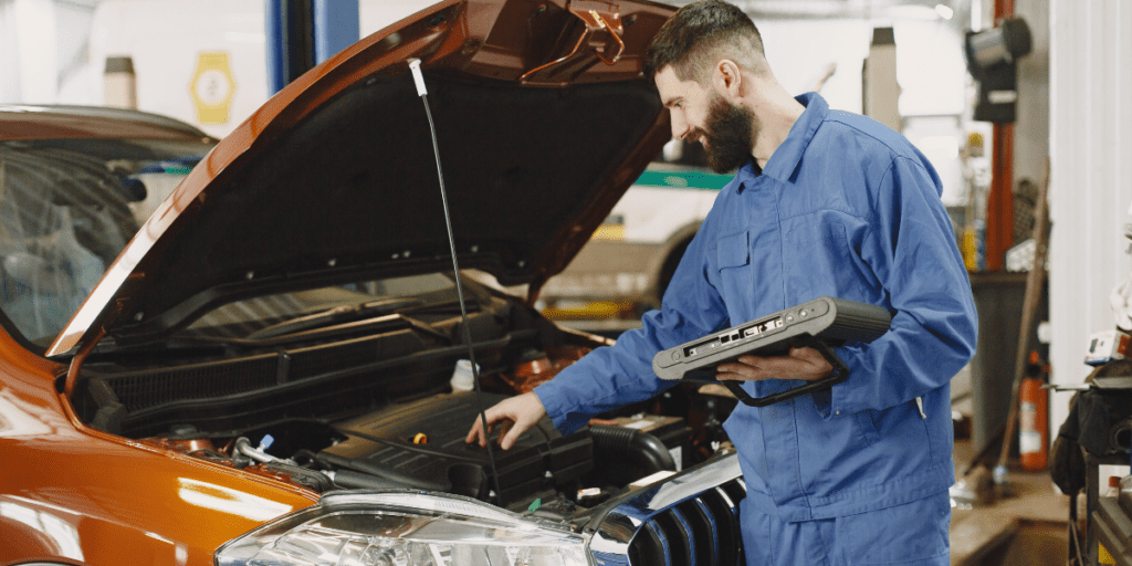 Mechanic inspecting car engine for repairs before selling the car.