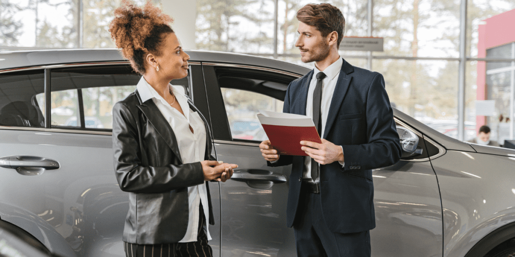 Professional car buyer discussing selling your car options with a customer at a dealership.