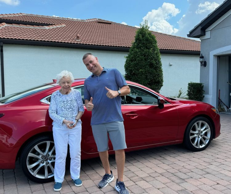 Happy customer in Sarasota posing with Ho Ho Buys Cars representative after selling their car for cash.